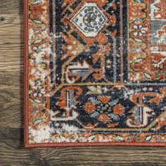 an orange and blue rug on a wooden floor with a wood wall in the background