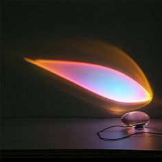 a lamp that is sitting on top of a table next to a light emitting from it