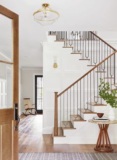 an entryway with stairs and potted plants on the table in front of it