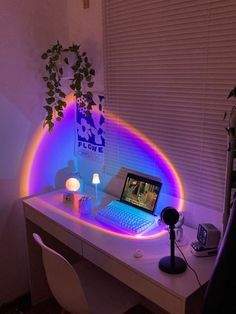 a laptop computer sitting on top of a white desk next to a plant and lamp