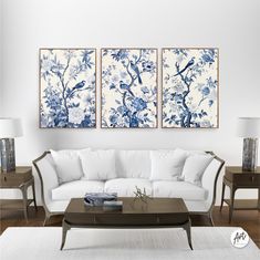 two blue and white paintings hang on the wall above a couch in a living room