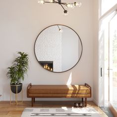 a living room with a large round mirror on the wall and a bench in front of it