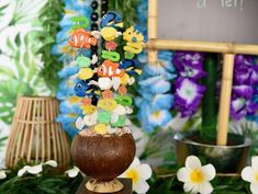 an arrangement of beads and flowers in a vase on a table with a chalkboard