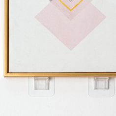 a painting is hanging on the wall with two plastic holders in front of it that hold an object