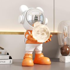 an orange and white robot holding a piece of bread in his hand while standing next to a stack of books