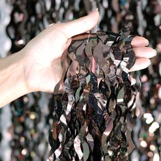 a hand is holding some black and silver crystals in front of a wall of mirrors