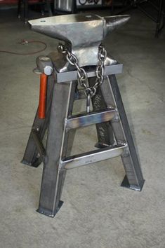 a metal stool with chains attached to the seat and foot rests on top of it