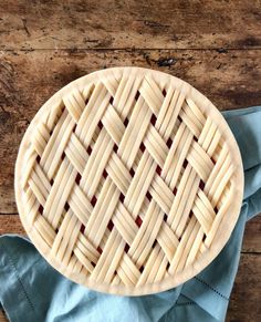 an uncooked pie sitting on top of a wooden table next to a blue napkin