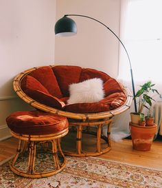 a chair and ottoman in a room with a lamp on the wall behind it, along with potted plants