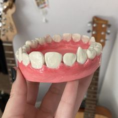 someone is holding up a fake tooth with white gums on it's teeth