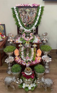 an arrangement of flowers and silver vases on a table