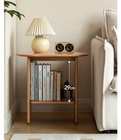 a wooden table with books and a lamp on it next to a couch in a living room