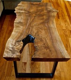 a wooden table with metal legs on a hard wood floor in a living room area