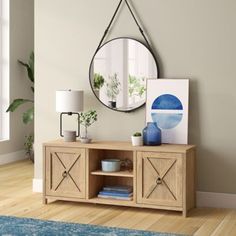 a living room with a mirror on the wall next to a wooden cabinet and blue rug