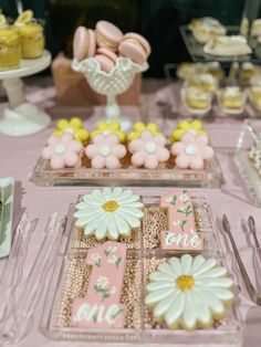 there are many desserts on the table with pink and white decorations, including flowers