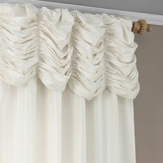 white curtains with pleated drapes hanging on a rod