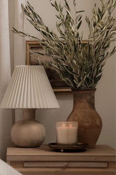 a table with a lamp, vase and candle on it