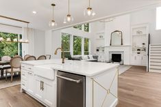 a large kitchen with an island in front of a dining room table and stairs leading up to the second floor