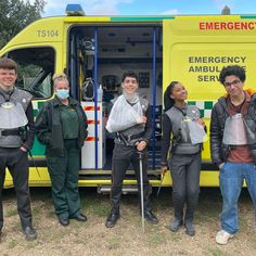 five people standing in front of an ambulance