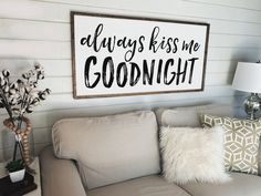 a living room with a gray couch and white pillows on the floor next to a wooden framed sign that says every love story is beautiful but bliss is my favorite