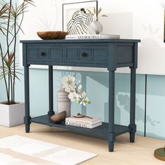 a blue console table with two drawers and a vase on the shelf next to it