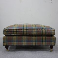 the footstool is upholstered and has a plaid pattern on it's sides