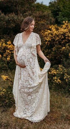 a pregnant woman wearing a white dress standing in the grass