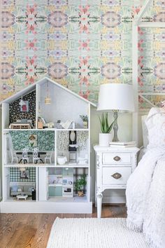 a bedroom with a bed, nightstand and wallpapered walls in pastel colors