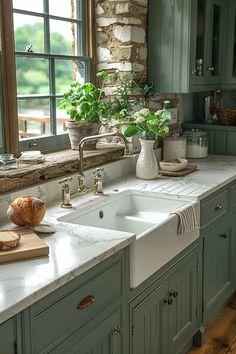 a kitchen with green cabinets and white counter tops, along with a large window over the sink