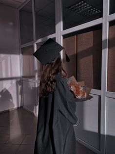 a woman wearing a graduation cap and gown is holding a tray with food in it