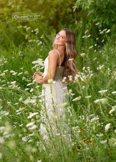 a beautiful young woman standing in the middle of tall grass and wildflowers with her eyes closed