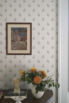 a vase filled with yellow flowers sitting on top of a table next to a painting