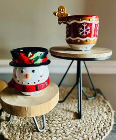 two bowls are sitting on small stools, one has a snowman hat and the other has a christmas decoration