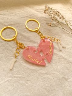 two pieces of pink heart shaped keychain sitting on top of a white sheet