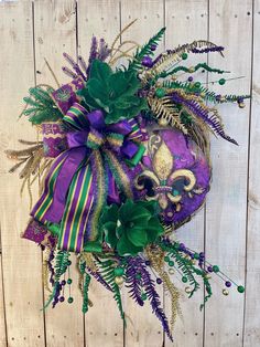 a purple mask with green and gold decorations on it's face, sitting against a wooden wall