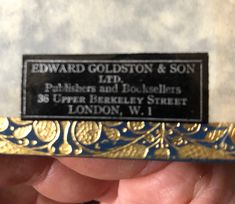 a close up of a person's hand holding a plaque that reads edward goldston & son ltd