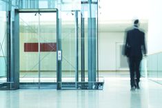 a man in a suit is walking through an open glass door at the entrance to a building