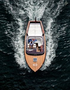 an overhead view of a small motor boat in the middle of the ocean with people on it