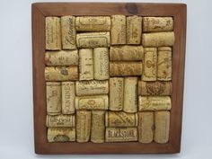 a wooden frame filled with wine corks on top of a white table next to a wall