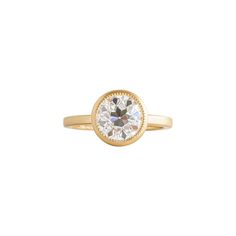 a yellow gold ring with a round cut diamond in the center, on a white background