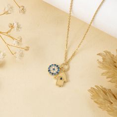 Esme Protect yourself in style with the Evil Eye & Hamsa Charm Necklace. This unique necklace features two protective charms: a sparkling blue sapphire Evil Eye and a diamond-studded Hamsa, both on a dainty solid gold chain. This beautiful piece wards off negativity and brings good luck, adding elegance to any outfit. Layer with other necklaces for a personalized look. - Handmade- Solid Gold- Natural Diamonds and Blue Sapphires- G Color, SI Quality Diamonds- Dimension: 7 mm- Total Diamond Carat Elegant Evil Eye Charm Necklace, Gold Plated Evil Eye Amulet Necklace, Gold Plated Evil Eye Amulet Jewelry, Evil Eye Amulet Pendant Charm Necklace, Evil Eye Hamsa, Protective Charms, Locket Design, Opal Hamsa Necklace, Charms Necklace