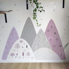 a wall painted with mountains and trees in pastel colors on the side of a room