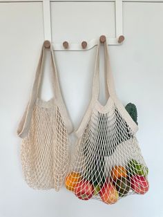 two bags hanging on the wall with fruit in them