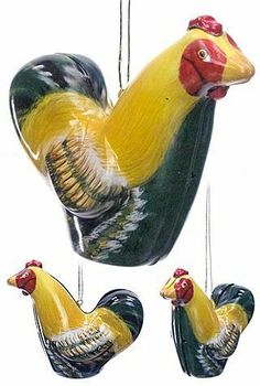 three ceramic roosters hanging from strings in the shape of hearts