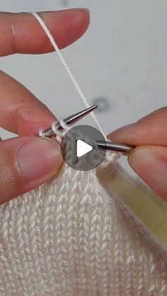 someone is knitting something with scissors on a piece of white yarn that has been crocheted