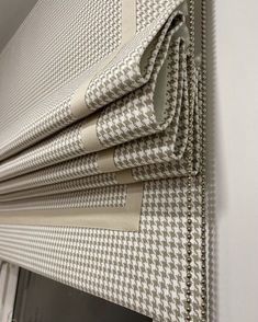 four pieces of white and brown checkered fabric hanging on the side of a window