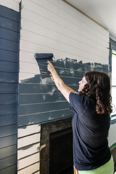 a woman is painting the wall in her living room with blue and white paint on it