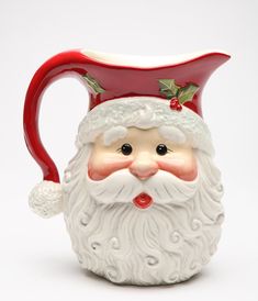 a ceramic santa claus mug with holly berries on its head and red nose, sitting in front of a white background