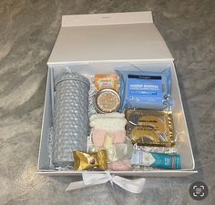 an open box with various items in it on a counter top next to a white ribbon