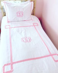 a pink and white bed with two monogrammed pillows